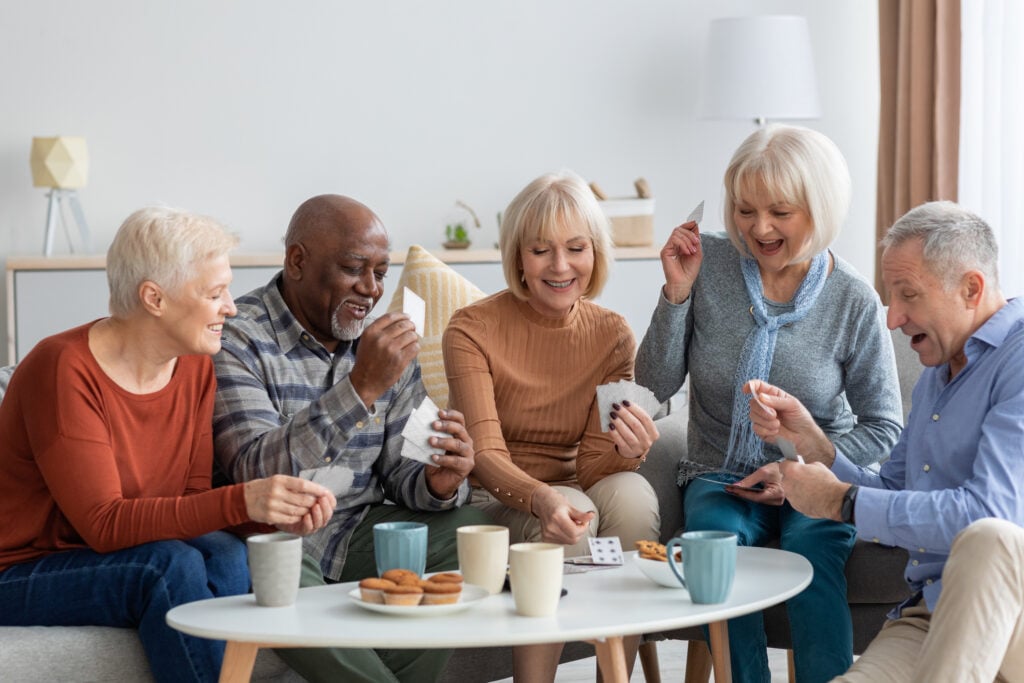 Group of older adults playing cards together and drinking coffee