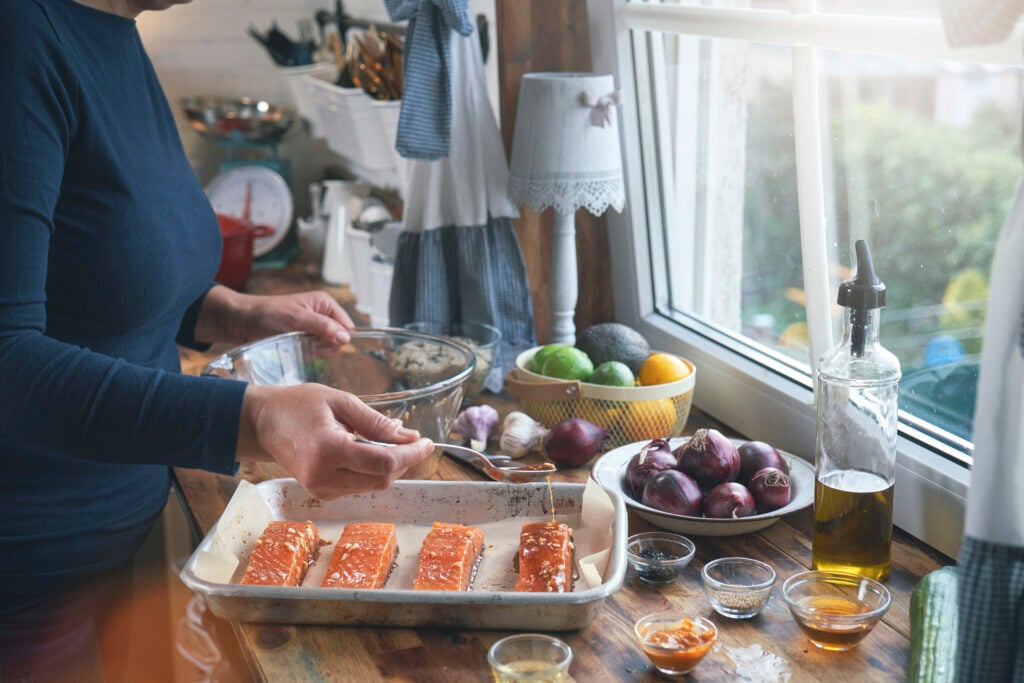 Woman prepares protein-filled salmon dinner.